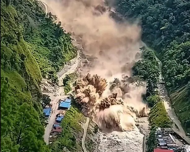 A destructive flood and debris surge moving through a steep river valley in Nepal