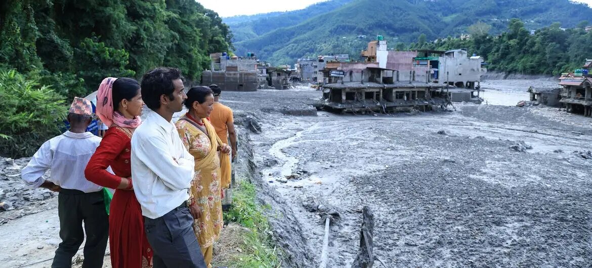 Nepalese residents looking across a settlement devastated by flood debris