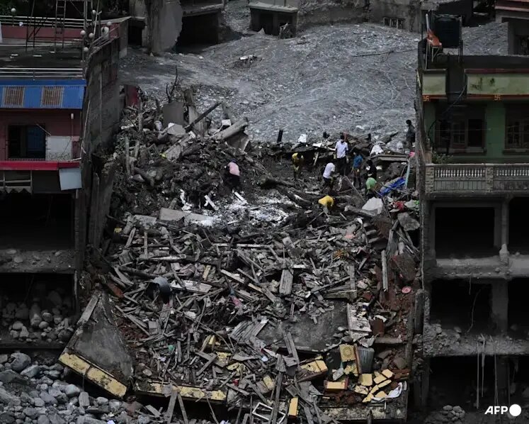 People searching through the remains of buildings destroyed by flooding